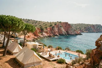 Vue panoramique d'un camping provençal avec tentes et mobil-homes sous les pins parasols face à la mer turquoise du Var