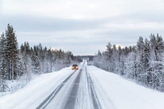 voiture circulant sur une route enneigée en montagne