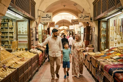 Famille en visite dans le souk traditionnel de Deira à Dubaï, entourée d'étals d'épices et de bijoux en or