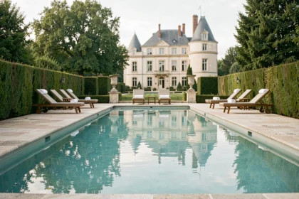 Piscine extérieure d'un hôtel de luxe dans les Hauts-de-France avec terrasse en pierre et vue sur un château
